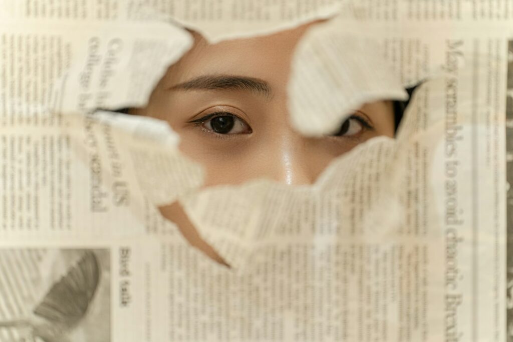 a woman looking through a hole in a newspaper
