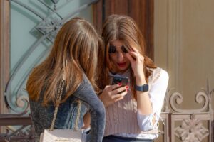 girls, looking, together, smartphone, outdoors, building, fence, lifestyle